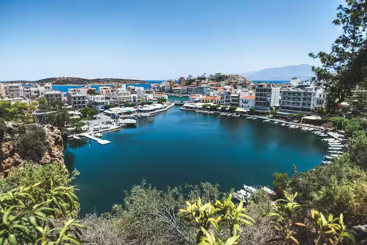 Elevated view of the deep, circular Lake Voulismeni, harbor, and waterfront promenade in the center of Agios Nikolaos, East Crete, Greece