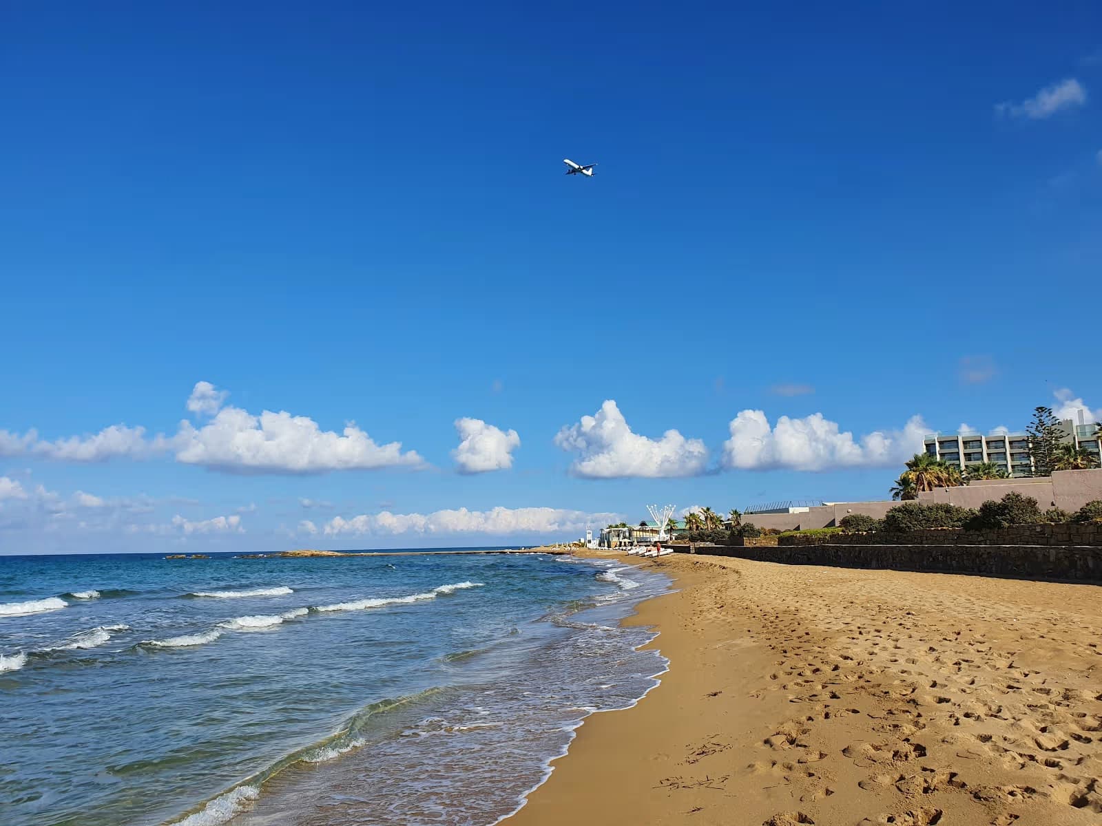 Sandy Arina Beach on the north coast of Crete, Heraklion, with clear blue water and resort hotel in the background